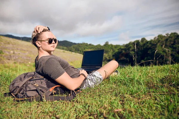 guy in nature with a laptop works