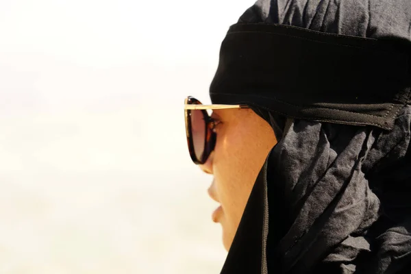 Siyah abaya 'da güneş gözlüklü güzel bir genç kadın portresi.