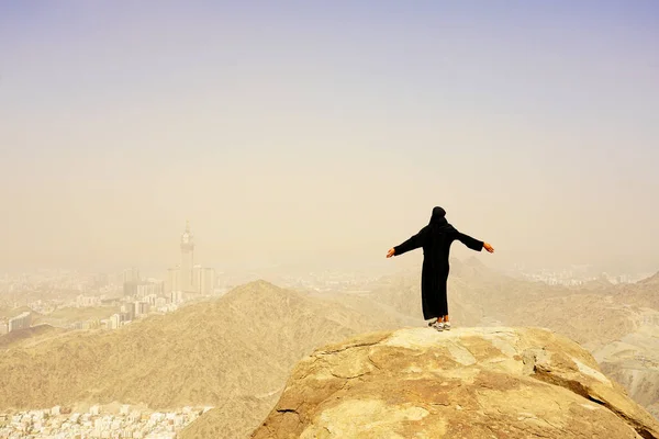 Ghar Thowr 'da, Mekke' de, Suudi Arabistan 'da, güneşli ve açık bir gökyüzünde tüm vücuda sahip genç Müslüman kadın portresi.