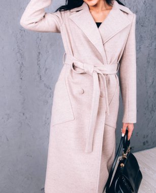 Dış giyimin ayrıntıları yakın plan. Yarı sezon kıyafetlerinin stüdyo fotoğrafçılığı. Gri arka planda zarif ceketli genç bir kız. Promosyon kadın ceketi. Şık bir sonbahar bahar montu giymiş bir kadın..