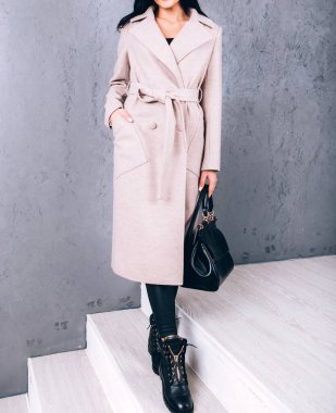 Yarı sezon kıyafetlerinin stüdyo fotoğrafçılığı. Gri arka planda zarif ceketli genç bir kız. Promosyon kadın ceketi. Şık bir sonbahar bahar montu giymiş bir kadın. Günlük kıyafet..