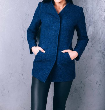 Dış giyimin ayrıntıları yakın plan. Yarı sezon kıyafetlerinin stüdyo fotoğrafçılığı. Gri arka planda zarif ceketli genç bir kız. Promosyon kadın ceketi. Şık bir sonbahar bahar montu giymiş bir kadın..