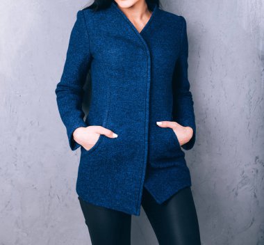 Dış giyimin ayrıntıları yakın plan. Yarı sezon kıyafetlerinin stüdyo fotoğrafçılığı. Gri arka planda zarif ceketli genç bir kız. Promosyon kadın ceketi. Şık bir sonbahar bahar montu giymiş bir kadın..