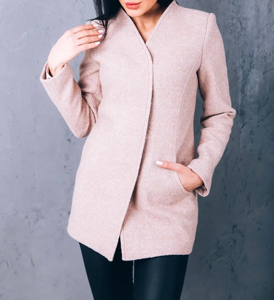 Detail of outerwear close-up. Studio photography of demi-season clothing. Young adult girl in an elegant coat on a gray background. Promotional women\'s coat. woman in a stylish autumn-spring coat.