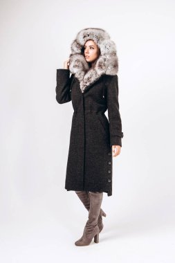 Beyaz arka planda kışlık ceketli bir kız. Şık giyimli, genç, modaya uygun bir kadın. Kürk kapüşonlu kışlık ceketli kız. Kışlık ceketli esmer bir kadının portresi..