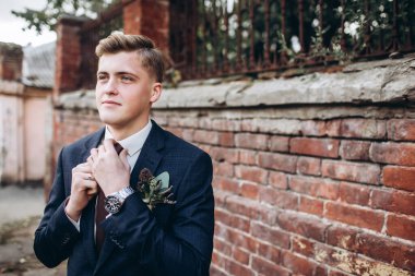 Takım elbiseli ve kravatlı vahşi bir damat. Sarışın adam eski kasabada geziniyor. Duvarın arkasında genç bir iş adamı var. Gülümseyen bir adam portosu..