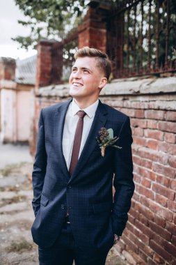 Takım elbiseli ve kravatlı vahşi bir damat. Sarışın adam eski kasabada geziniyor. Duvarın arkasında genç bir iş adamı var. Gülümseyen bir adam portosu..