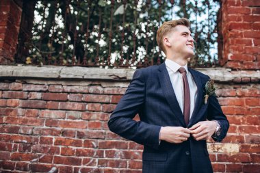 Takım elbiseli ve kravatlı vahşi bir damat. Sarışın adam eski kasabada geziniyor. Duvarın arkasında genç bir iş adamı var. Gülümseyen bir adam portosu..