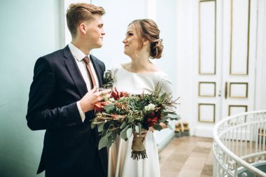 Eski bir malikanede gelinlik giymiş genç bir çift. Gelin ve damat içeride bir düğün töreninde. Sevgi dolu bir çift. Duygular. Mutlu karı koca. Elinde bir buket sonbahar çiçeğiyle gelin..