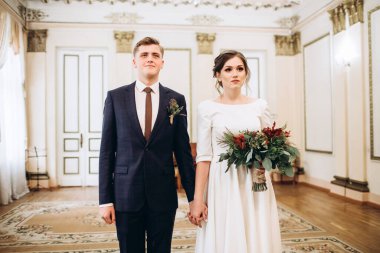 Eski bir malikanede gelinlik giymiş genç bir çift. Gelin ve damat içeride bir düğün töreninde. Sevgi dolu bir çift. Duygular. Mutlu karı koca. Elinde bir buket sonbahar çiçeğiyle gelin..