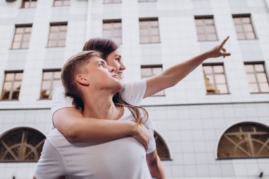 Sonbahar günü şehirde yürüyen genç bir çift. Mutlu çift sarılıp gülüyor. Gerçek duygular. Yakın plan bir çift portre. Güneşli bir günde bir erkek ve bir kadın dışarı çıkar..