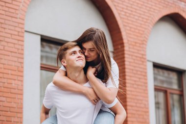 Sonbahar günü şehirde yürüyen genç bir çift. Mutlu çift sarılıp gülüyor. Gerçek duygular. Yakın plan bir çift portre. Güneşli bir günde bir erkek ve bir kadın dışarı çıkar..