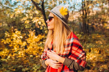 Gri şapkalı bir sarışın sonbahar ormanında yürüyor. Kırmızı ceketli neşeli kız güneşli bir sonbahar gününde gölde oturur. Ormanda yürüyen bir kadın.
