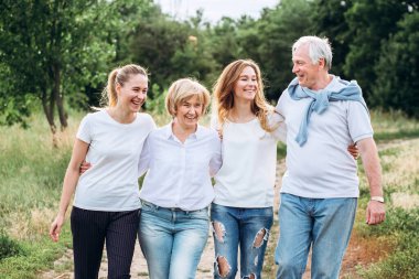 Yetişkin kızları olan yaşlı bir çift doğada yürür. Olgun bir çift ormanda yürüyor. Beyaz tişörtlü ve kot pantolonlu bir aile parkta yürüyor. Mutlu bir aile. Aile dışarıda iletişim kurar.