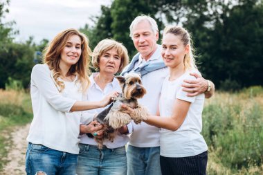 Yetişkin kızları olan yaşlı bir çift doğada yürür. Yetişkin bir çift bir köpekle ormanda yürüyor. Beyaz tişörtlü ve kot pantolonlu bir aile parkta yürüyor. Aile dışarıda iletişim kurar.