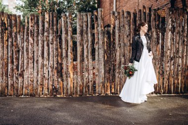 Mütevazı bir elbise içindeki güzel bir gelinin portresi. Uzun kollu, beyaz elbiseli esmer kız. Sonbahar buketi olan tatlı bir gelin. Bir sonbahar sokağında açık havada bir kadının portresi..