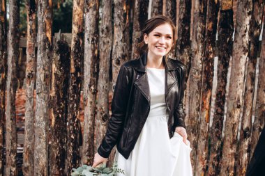 Mütevazı bir elbise içindeki güzel bir gelinin portresi. Uzun kollu, beyaz elbiseli esmer kız. Sonbahar buketi olan tatlı bir gelin. Bir sonbahar sokağında açık havada bir kadının portresi..