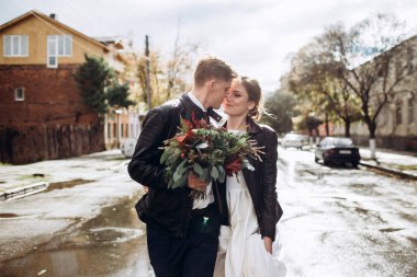 Genç mutlu çift yağmurdan sonra bir şehir caddesinde yürüyor. Bir erkek ve kadının yakın plan portresi. Dışarıda gülümseyen sevimli bir çift. Şehirde güneşli bir sonbahar günü.