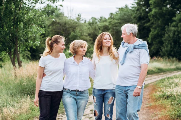 Yetişkin kızları olan yaşlı bir çift doğada yürür. Olgun bir çift ormanda yürüyor. Beyaz tişörtlü ve kot pantolonlu bir aile parkta yürüyor. Mutlu bir aile. Aile dışarıda iletişim kurar.