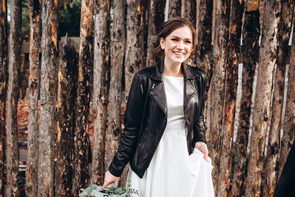 Portrait of a beautiful bride in a modest dress. Young brunette girl in a white dress with long sleeves. Cute bride with an autumn bouquet. Portrait of a woman outdoors on an autumn street.