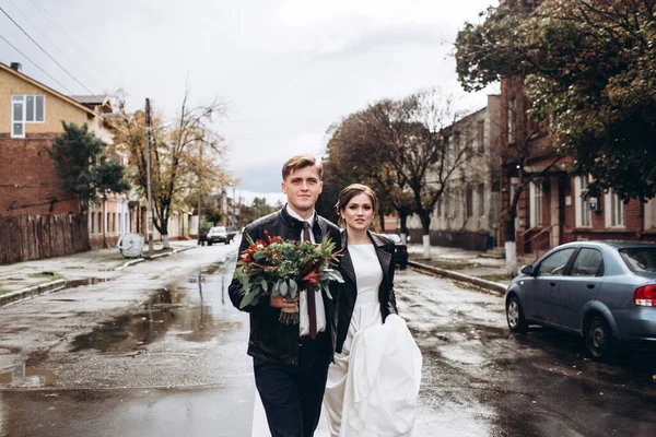 Genç mutlu çift yağmurdan sonra bir şehir caddesinde yürüyor. Bir erkek ve kadının yakın plan portresi. Dışarıda gülümseyen sevimli bir çift. Şehirde güneşli bir sonbahar günü.