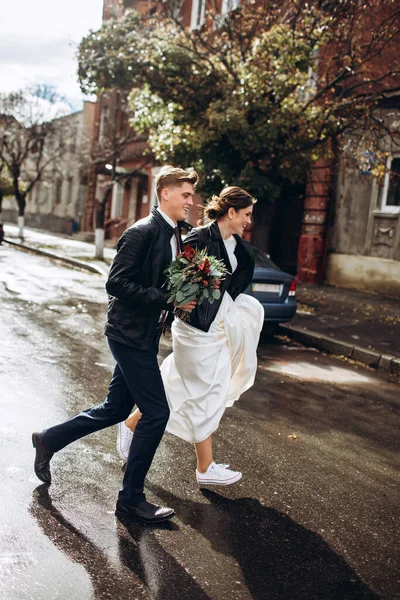 Genç mutlu çift yağmurdan sonra bir şehir caddesinde yürüyor. Bir erkek ve kadının yakın plan portresi. Dışarıda gülümseyen sevimli bir çift. Şehirde güneşli bir sonbahar günü.