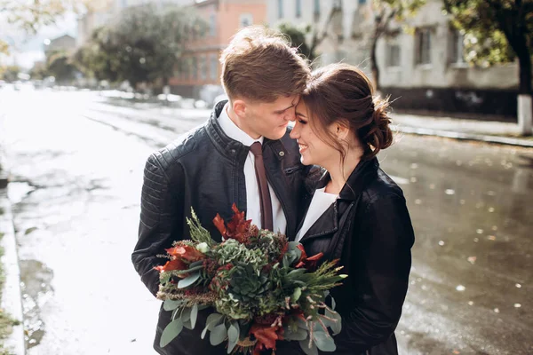 Genç mutlu çift yağmurdan sonra bir şehir caddesinde yürüyor. Bir erkek ve kadının yakın plan portresi. Dışarıda gülümseyen sevimli bir çift. Şehirde güneşli bir sonbahar günü.