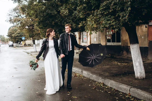 Genç mutlu çift yağmurdan sonra bir şehir caddesinde yürüyor. Şemsiyeli bir erkek ve kadının yakın plan portresi. Dışarıda gülümseyen sevimli bir çift. Bir adam sokakta yürüyor ve elinde şemsiyeyle