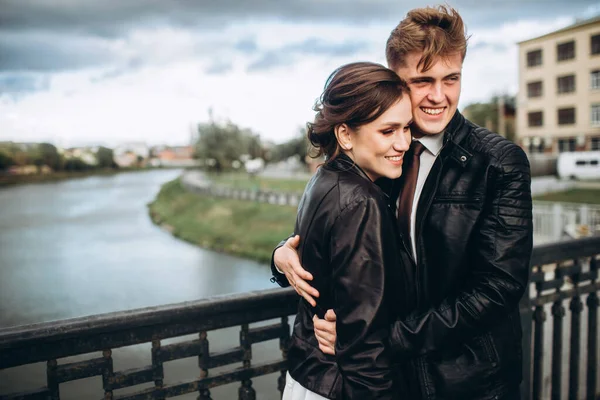 Young Couple Cuddling Bridge River Bride Groom Leather Jackets Loving — Stock Photo, Image