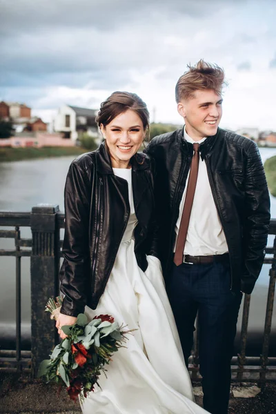 Молодая Пара Обнимается Мосту Через Реку Жених Невеста Кожаных Куртках Стоковое Изображение