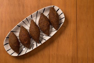 Kızarmış kibbeh, bir tabakta servis edilir, ahşap arka planda.