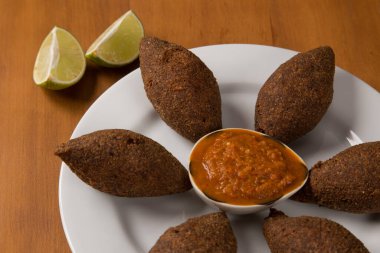 Kızarmış kibbeh beyaz bir tabakta biber sosuyla servis edilir..