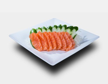 SALMON SASHIMI Dilimleri, beyaz bir tabakta servis edilir..