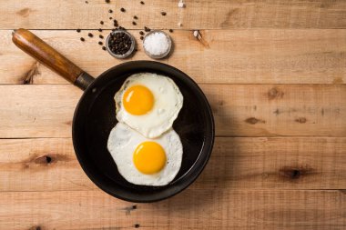 Kızarmış yumurta, tavada, ahşap arka planda. Üst Wiew.