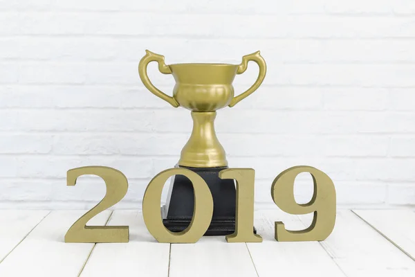 2019 new year and golden trophy on white wood table over white background with copy space , winner or success concept