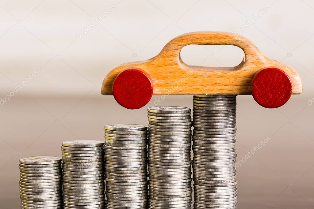 Stack of coins with wooden toy on wood table