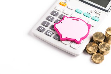 Hesap makinesiyle şekillendirilmiş domuz kumbarası ve beyaz arkaplanda altın sikkeler