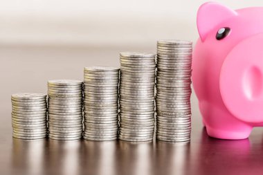 Ahşap masada kumbarası olan bir yığın bozuk para.