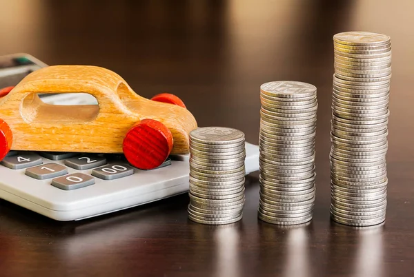 Hesap makineli bozuk para yığını ve ahşap masada ahşap bir araba.