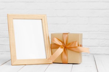 Fotoğraf çerçevesi ve hediye kutusu beyaz ahşap masanın üzerinde. Fotokopi sapıyla birlikte..