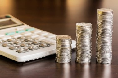 Tahta masanın üzerinde hesap makinesi olan bozuk para yığını