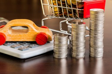 Hesap makineli bozuk para yığını ve ahşap masada ahşap bir araba.