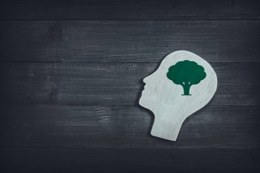 Ahşap masa üzerinde yeşil ağaç işareti olan insan kafası ve yüzü.