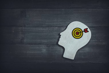 Ahşap masa sırtında dart tahtası işareti olan insan kafası ve yüzü