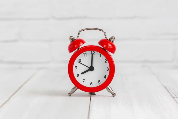 Alarm clock on white wood table over white brick background with