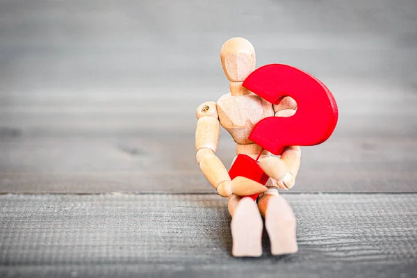 Jointed Wooden Doll hugging red question mark — Stockfoto