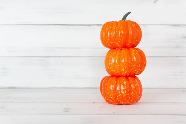 Pilha de abóbora laranja na mesa de madeira branca com espaço de cópia . — Fotografia de Stock