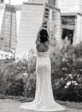 Arkası açık, zarif, beyaz elbiseli gelin kameraya arkası dönük duruyor. Düğün günü, arkası açık gelinlik. Dantel, dantel elbise