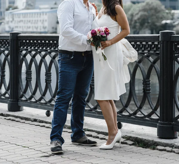 Беременная невеста в тонком белом платье на тонких спагетти с голыми плечами с букетом пионов — стоковое фото