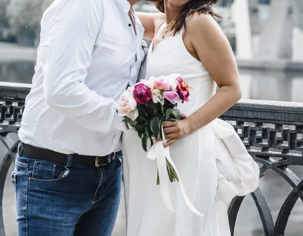 Беременная невеста в тонком белом платье на тонких спагетти с голыми плечами с букетом пионов — стоковое фото